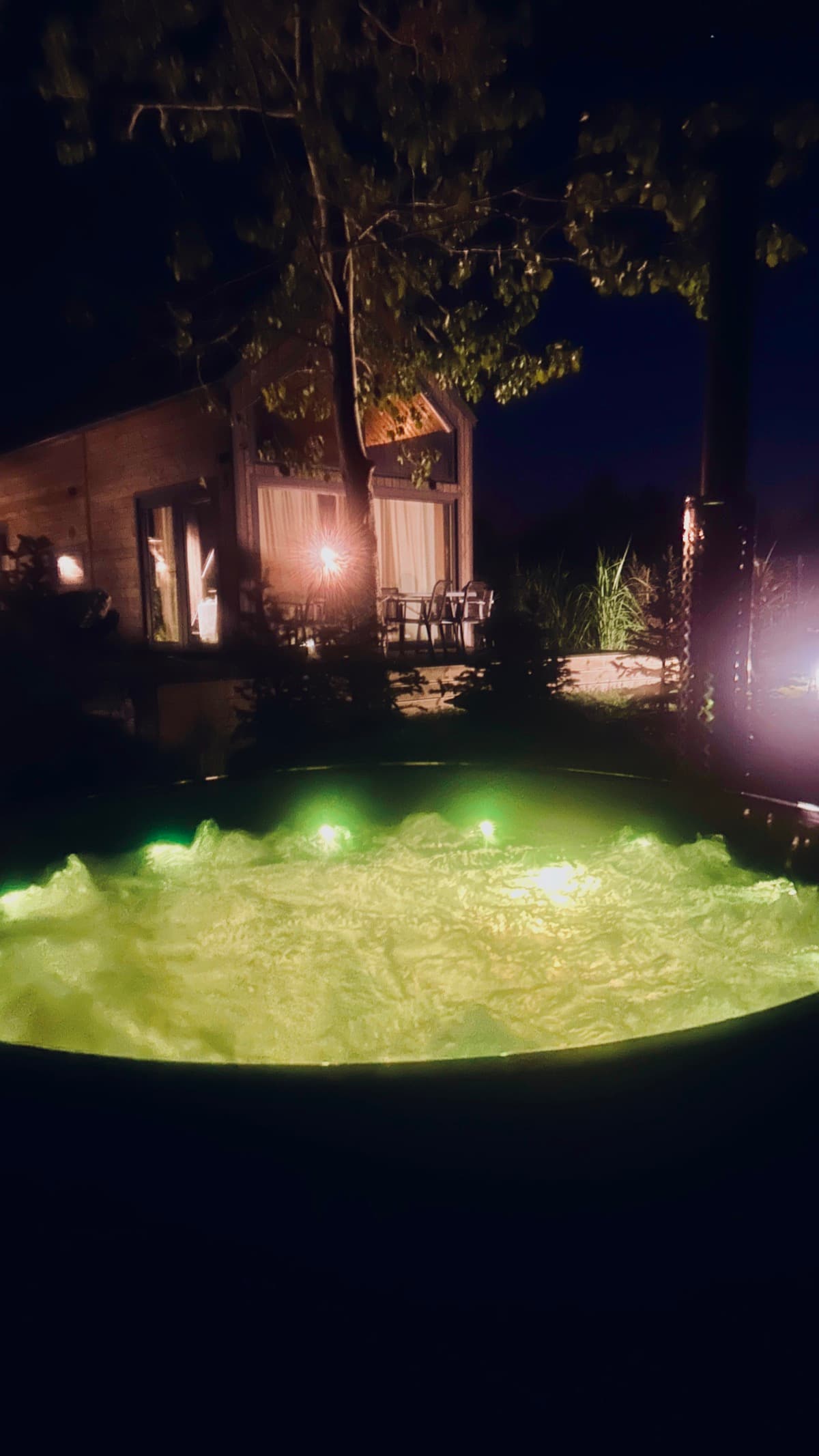 Balia z zielonym podświetleniem nocą na tle domku