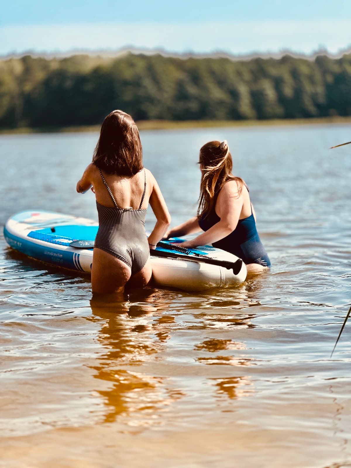Dziewczyna na desce SUP w słoneczny dzień na jeziorze